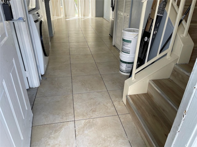 hallway with light tile patterned floors, stairs, and washer / clothes dryer