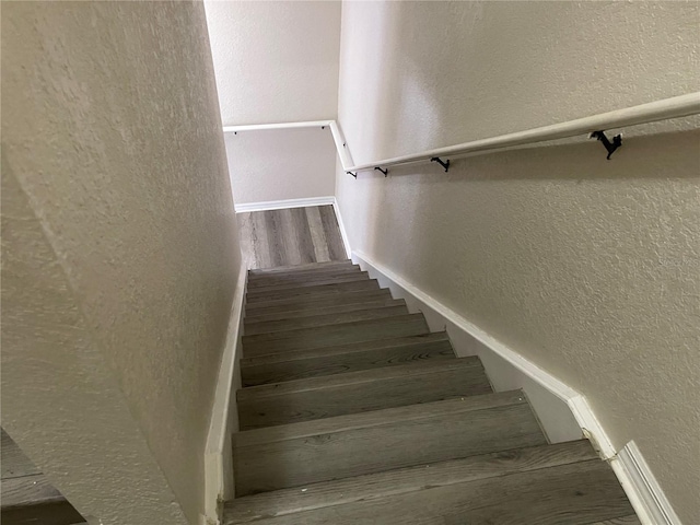 stairway featuring a textured wall and wood finished floors