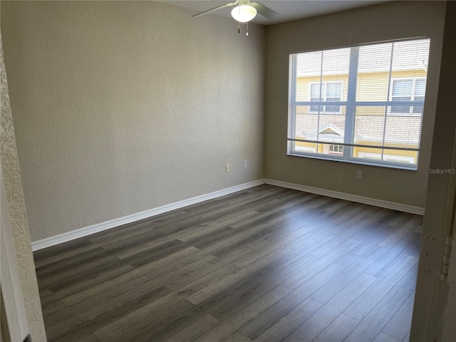 spare room with ceiling fan, dark wood-style floors, and baseboards