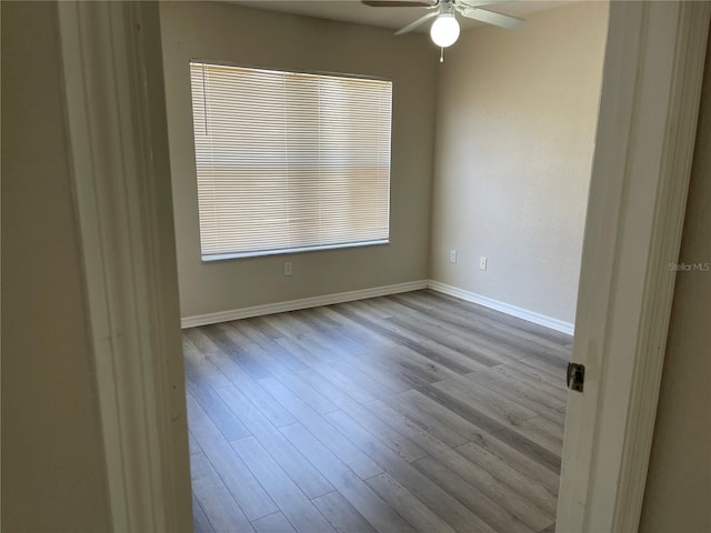 spare room featuring baseboards, ceiling fan, and wood finished floors