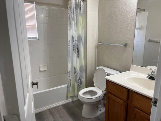 bathroom featuring a textured wall, vanity, toilet, wood finished floors, and shower / tub combo