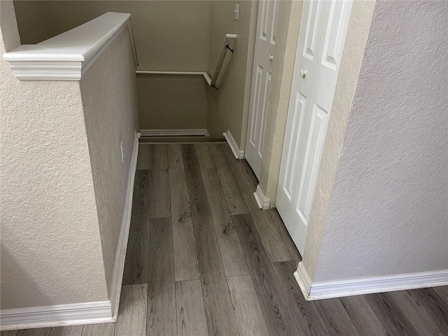 hall with a textured wall and wood finished floors