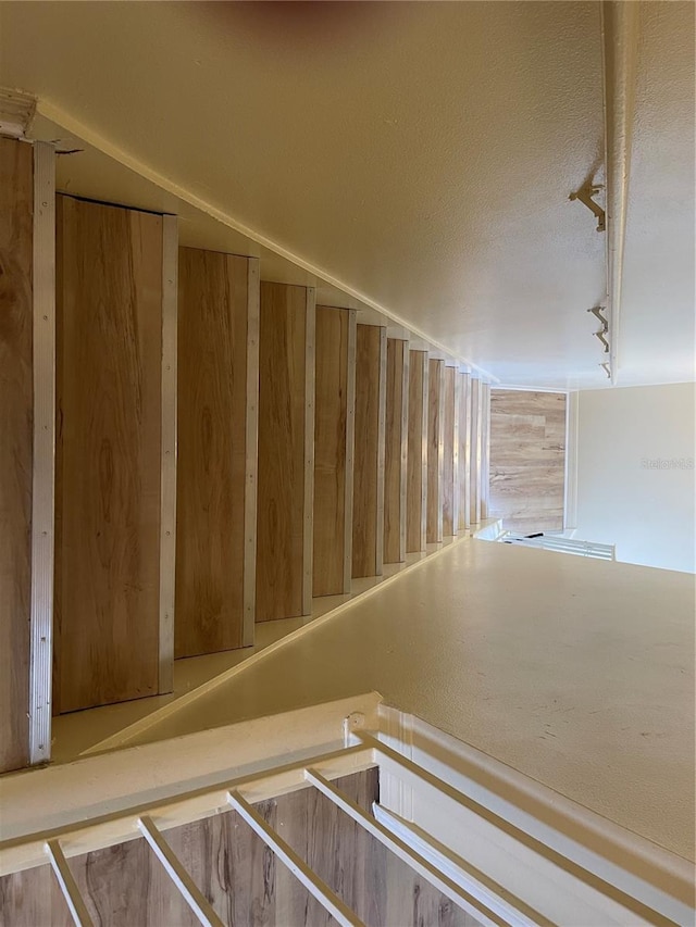 staircase featuring rail lighting and a textured ceiling