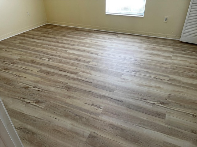 empty room featuring baseboards and light wood finished floors