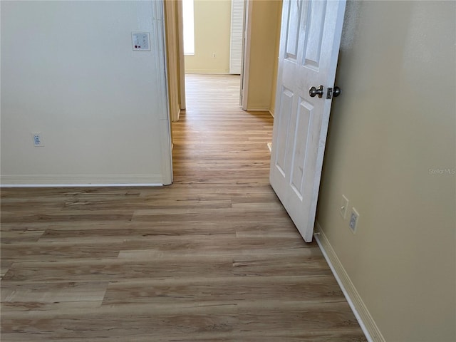 hall with baseboards and light wood-style flooring