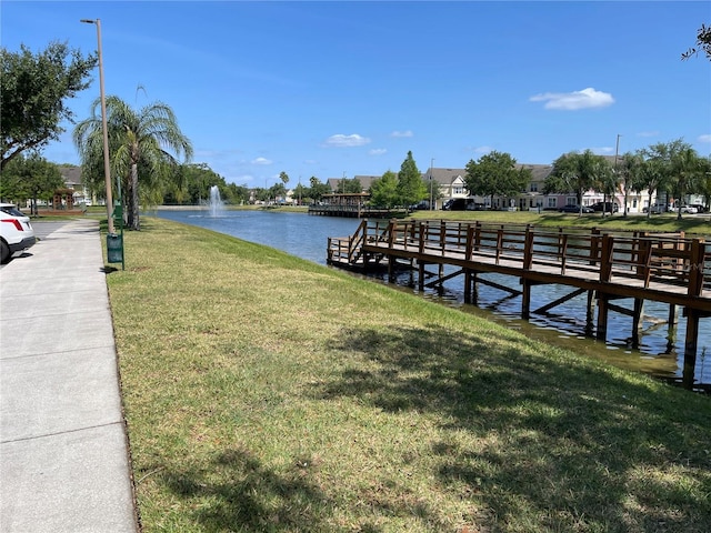 dock area with a yard, a water view, and a residential view