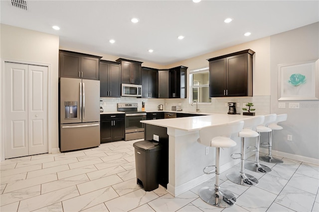 9034 Stinger Dr, Davenport, FL 33896 - kitchen with visible vents, marble finish floor, a peninsula, a breakfast bar area, and appliances with stainless steel finishes