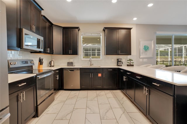 9034 Stinger Dr, Davenport, FL 33896 - kitchen with marble finish floor, a peninsula, recessed lighting, a sink, and stainless steel appliances