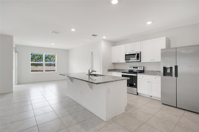 kitchen featuring a sink, stone counters, a kitchen island with sink, and stainless steel appliances