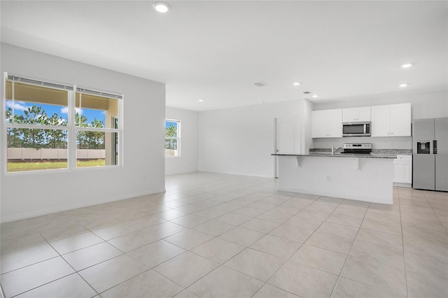 unfurnished living room with light tile patterned floors, baseboards, recessed lighting, and a sink