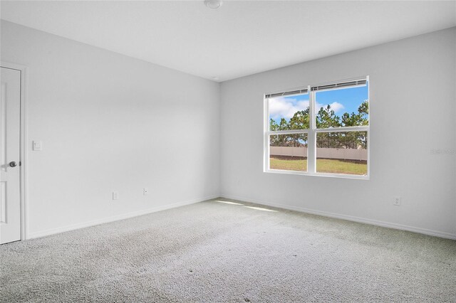 carpeted empty room featuring baseboards