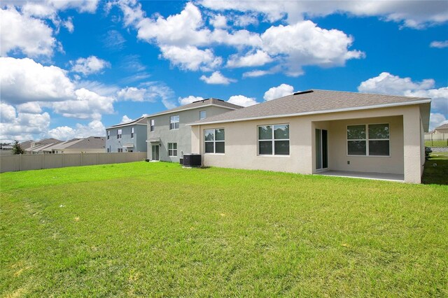 back of property with central air condition unit, a yard, fence, and stucco siding