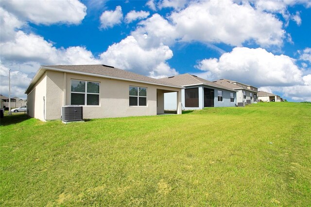 rear view of house with a lawn, stucco siding, and cooling unit