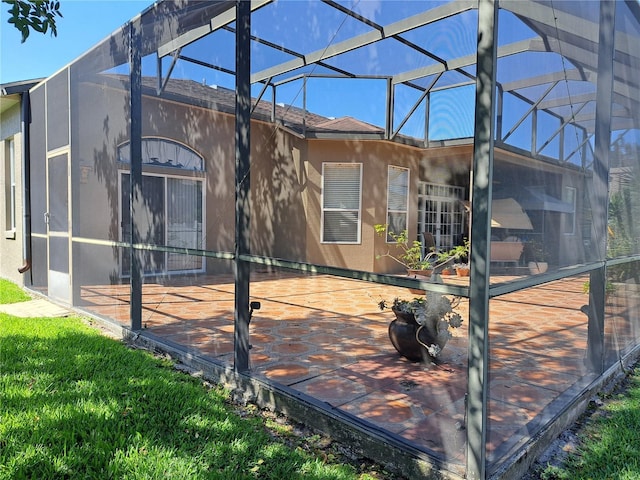 back of property with roof with shingles, a lanai, a patio area, and stucco siding