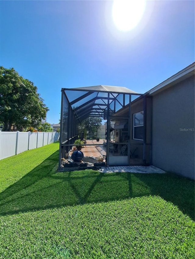 view of yard with fence, a lanai, and a patio area
