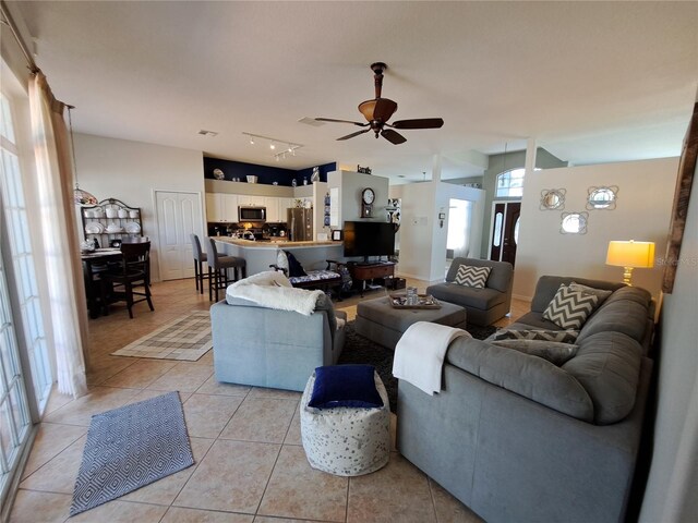 living area featuring light tile patterned flooring, a ceiling fan, visible vents, and rail lighting