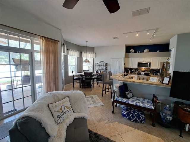 living room featuring a ceiling fan, visible vents, and light tile patterned floors