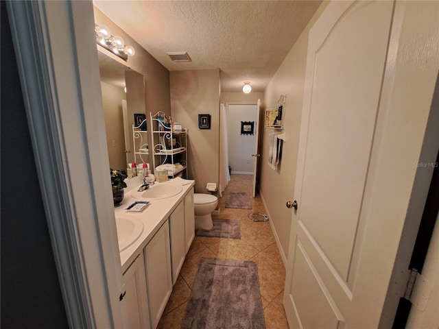 bathroom featuring a textured ceiling, visible vents, tile patterned flooring, a sink, and toilet
