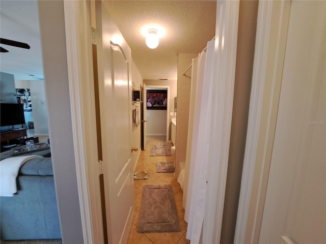 hallway with a textured ceiling and light tile patterned floors