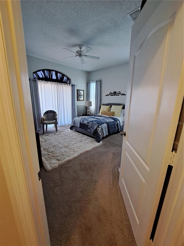 bedroom featuring carpet flooring, a ceiling fan, a textured ceiling, and visible vents