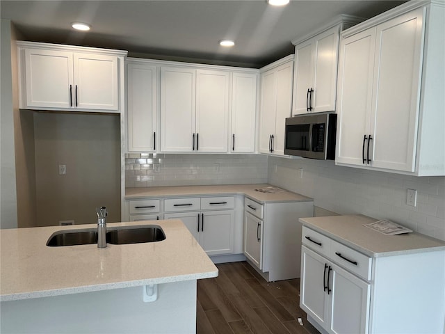 kitchen featuring stainless steel microwave, a sink, recessed lighting, dark wood finished floors, and white cabinetry