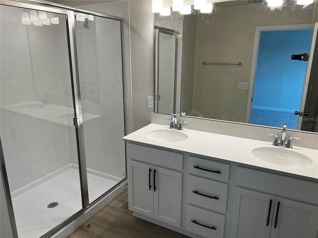 full bath with a stall shower, wood finished floors, double vanity, and a textured wall