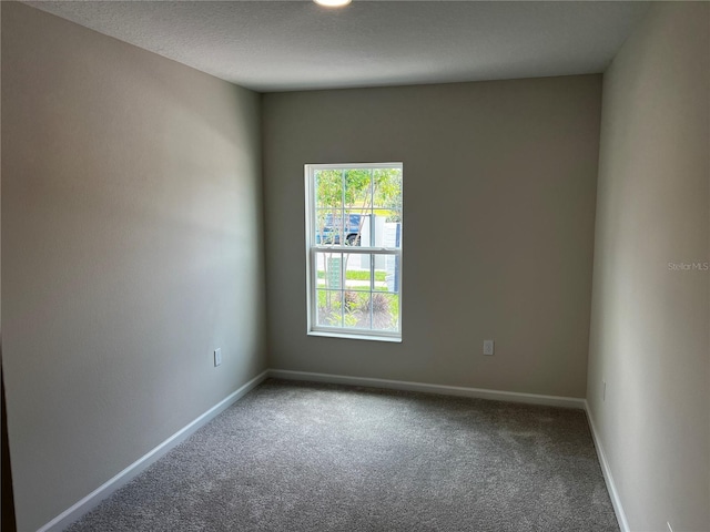 carpeted empty room featuring baseboards