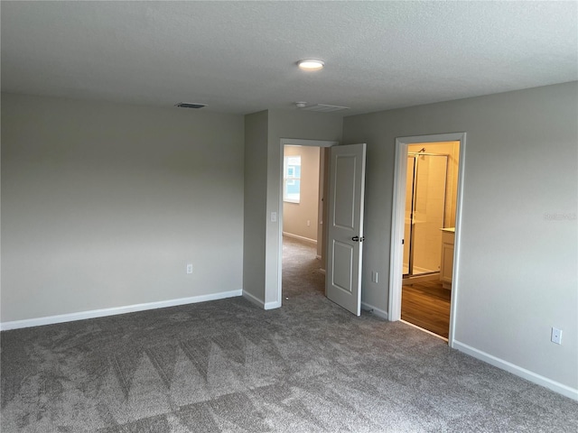 unfurnished room featuring dark colored carpet, baseboards, and a textured ceiling