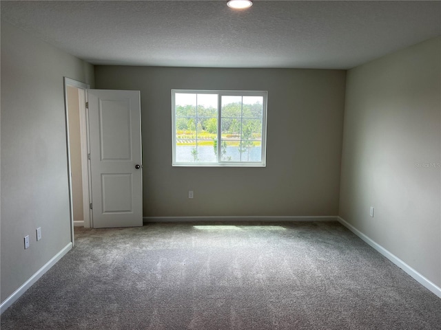 carpeted empty room with baseboards, a textured ceiling, and recessed lighting