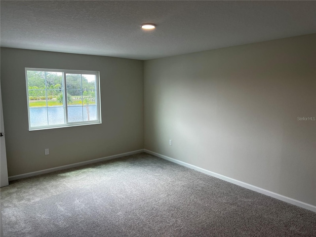carpeted empty room with baseboards and a textured ceiling