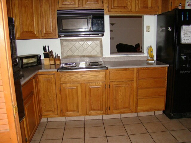 11624 Delmar Ave, Orlando, FL 32836 - kitchen featuring brown cabinetry, light tile patterned flooring, and black appliances