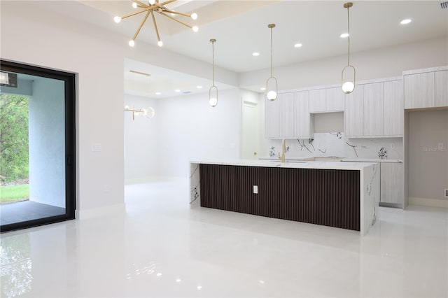 kitchen featuring light tile patterned flooring, a notable chandelier, a sink, an island with sink, and modern cabinets