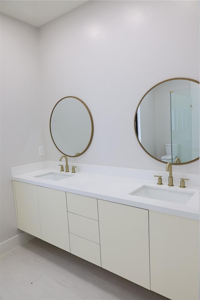 bathroom with a sink, tile patterned flooring, toilet, and double vanity