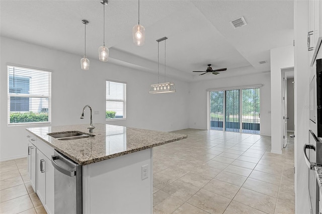 kitchen with a sink, dishwasher, a tray ceiling, light tile patterned floors, and open floor plan