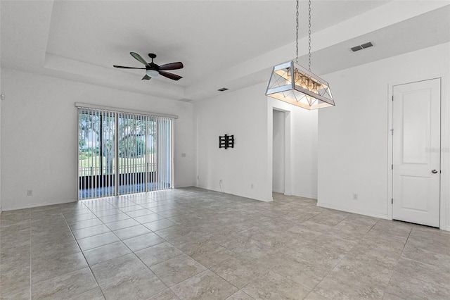 spare room with a tray ceiling, ceiling fan, and baseboards