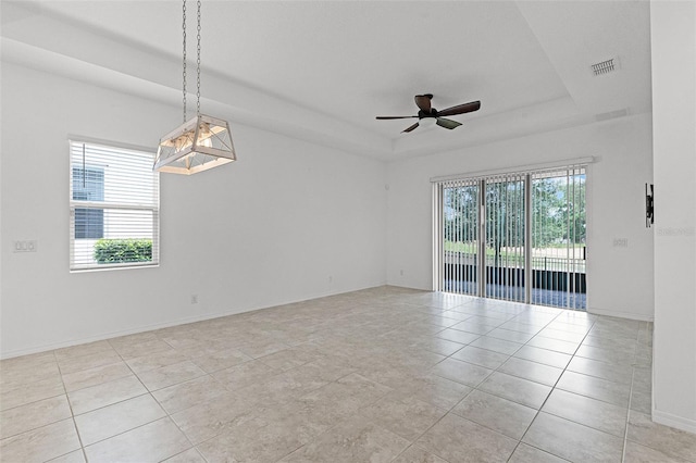 spare room featuring a tray ceiling, ceiling fan, light tile patterned floors, and baseboards