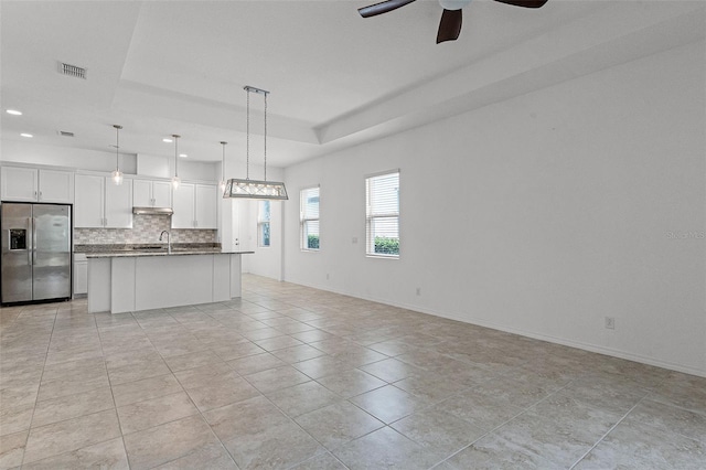 kitchen with stainless steel fridge with ice dispenser, open floor plan, a sink, recessed lighting, and backsplash