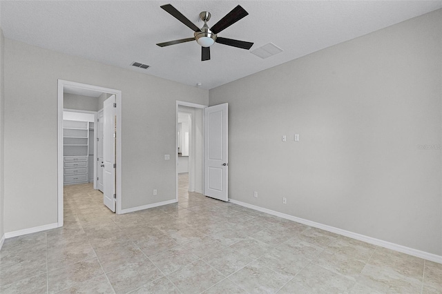 unfurnished bedroom with a spacious closet, ceiling fan, light tile patterned floors, a closet, and baseboards