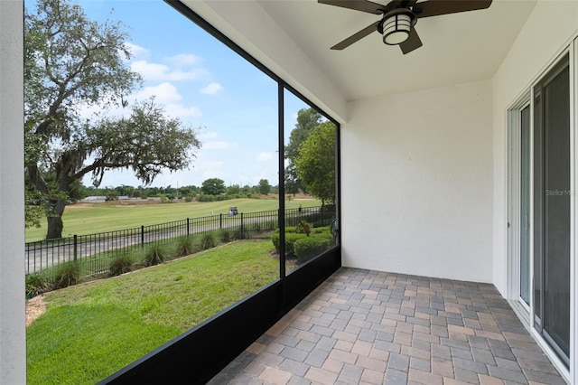 unfurnished sunroom with a ceiling fan and view of golf course