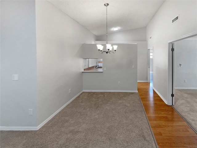 unfurnished dining area with carpet flooring, visible vents, baseboards, a chandelier, and lofted ceiling