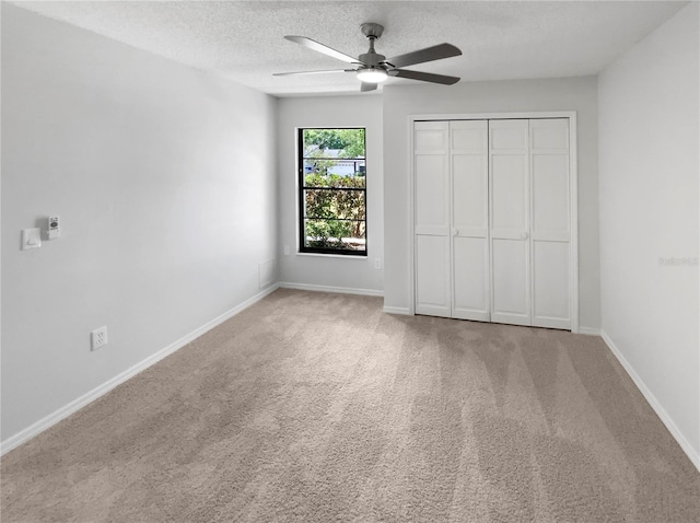 unfurnished bedroom featuring a closet, baseboards, a textured ceiling, a ceiling fan, and carpet