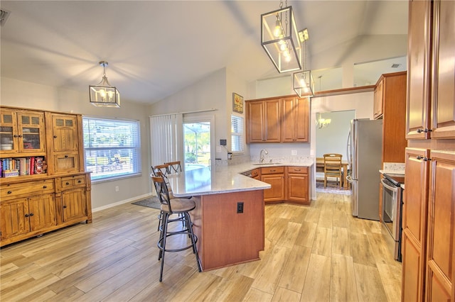 kitchen featuring stainless steel appliances, vaulted ceiling, a peninsula, a sink, and a chandelier