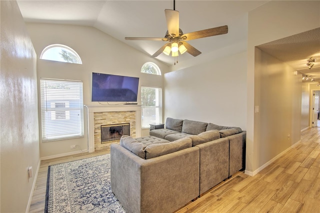 living area featuring vaulted ceiling, a ceiling fan, light wood-style floors, plenty of natural light, and a fireplace