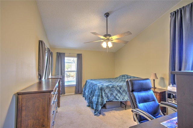 bedroom featuring light carpet, a textured ceiling, lofted ceiling, a desk, and ceiling fan