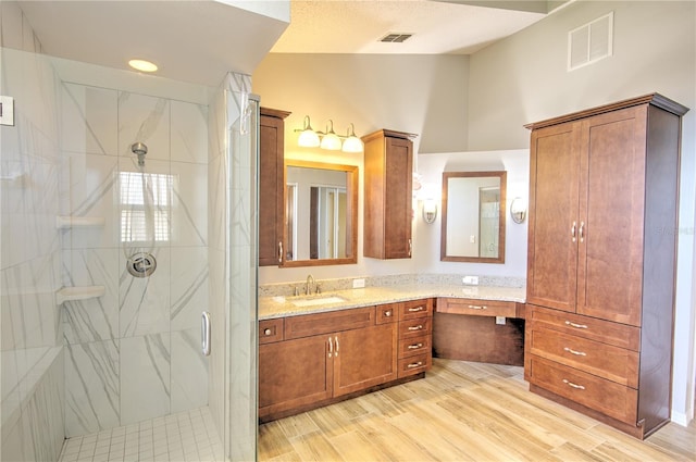 full bathroom with a marble finish shower, wood finished floors, and vanity