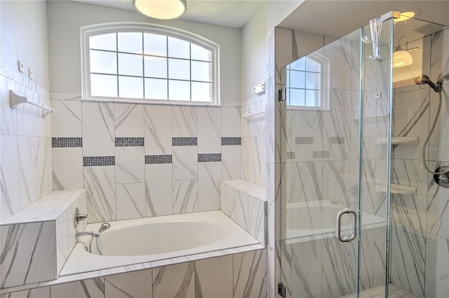 bathroom with plenty of natural light, combined bath / shower with glass door, and tile walls