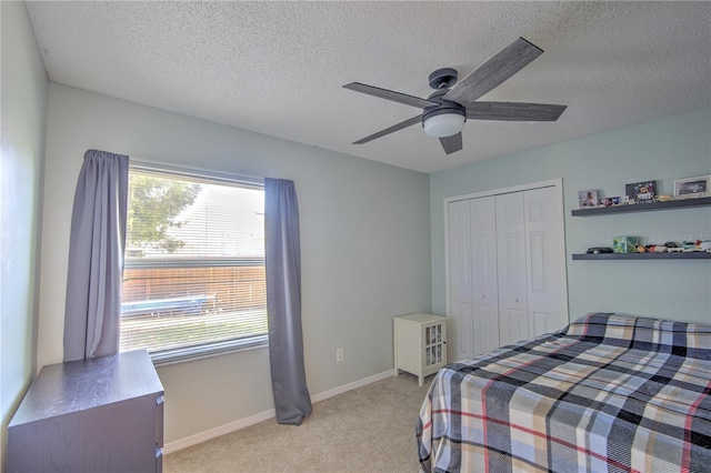 bedroom with multiple windows, light colored carpet, a closet, a textured ceiling, and ceiling fan