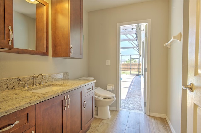 half bathroom featuring toilet, vanity, wood finished floors, and baseboards