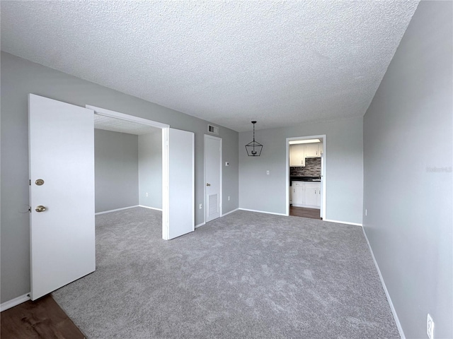 unfurnished room with baseboards, dark colored carpet, visible vents, and a textured ceiling