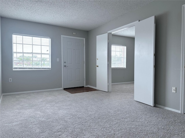 carpeted foyer featuring baseboards and a textured ceiling